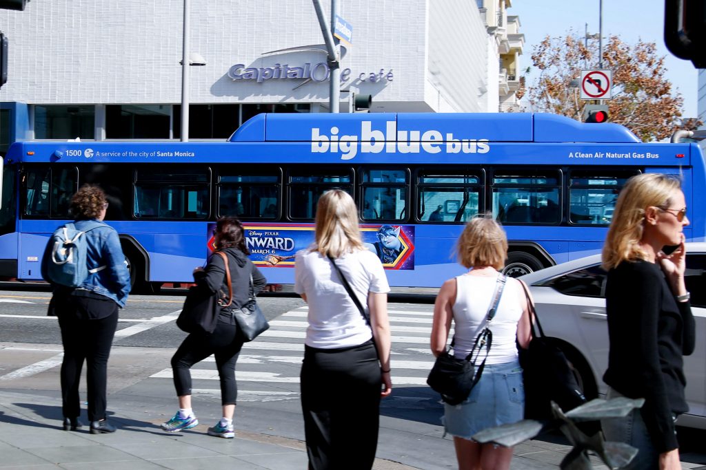 big bue bus santa monica with advertising on it and crowds in the area